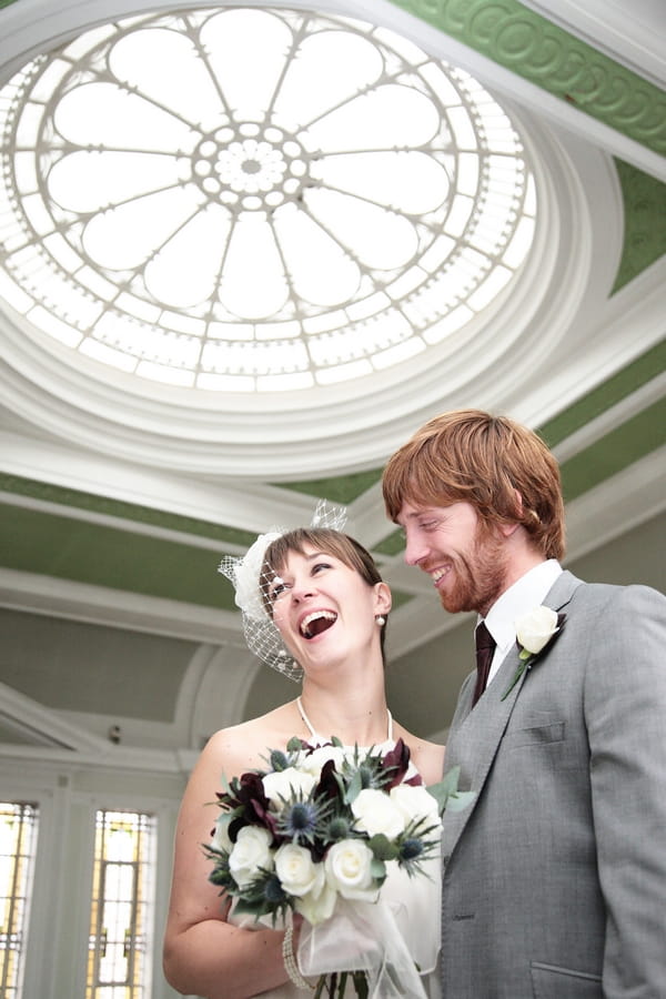 Bride smiling with groom under large skylight - Picture by Rebecca Prigmore Photography