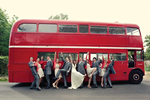 Wedding party posing for photograph in front of red double decker bus - A Homemade Marquee Wedding