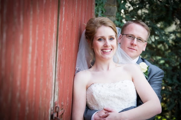 Bride and groom leaning on red door - Picture by Gareth Squance Photography