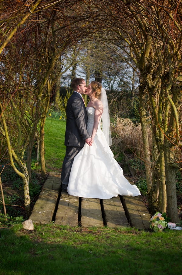 Bride and groom kissing on small wooden bridge - Picture by Gareth Squance Photography