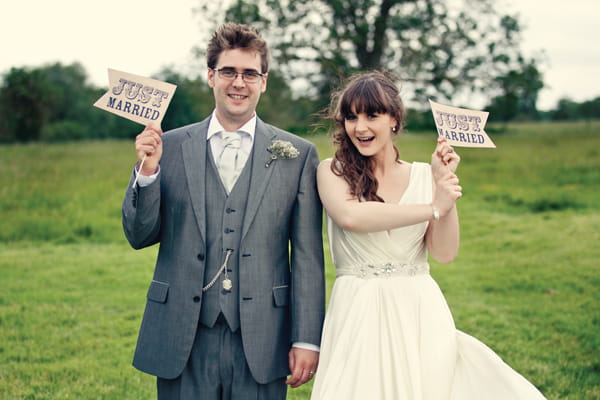 Bride and groom holding Just Married flags - A Homemade Marquee Wedding