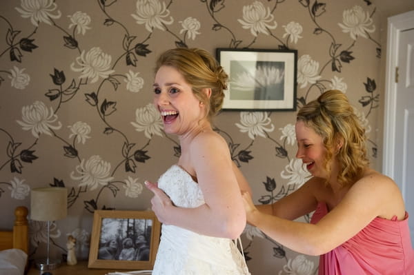 Bride laughing as her dress is fastened - Picture by Gareth Squance Photography