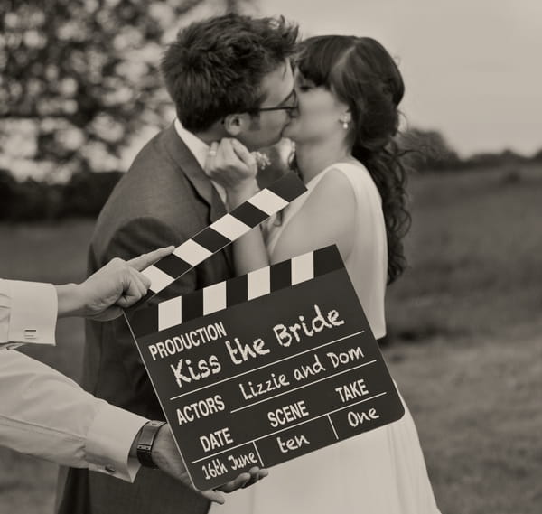 Bride and groom kissing behind a movie clapperboard - A Homemade Marquee Wedding