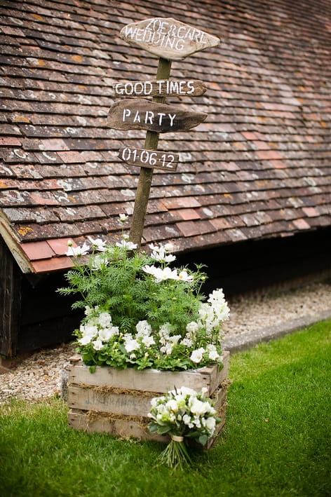 Wedding sign post with flowers below - A Beautiful Garden Party Wedding at Lains Barn