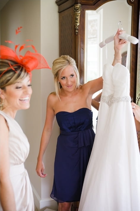 Bridesmaid holding up wedding dress - A Beautiful Garden Party Wedding at Lains Barn