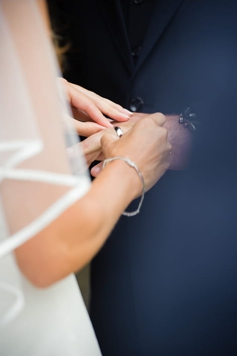 Bride placing ring on groom's finger - A Beautiful Garden Party Wedding at Lains Barn