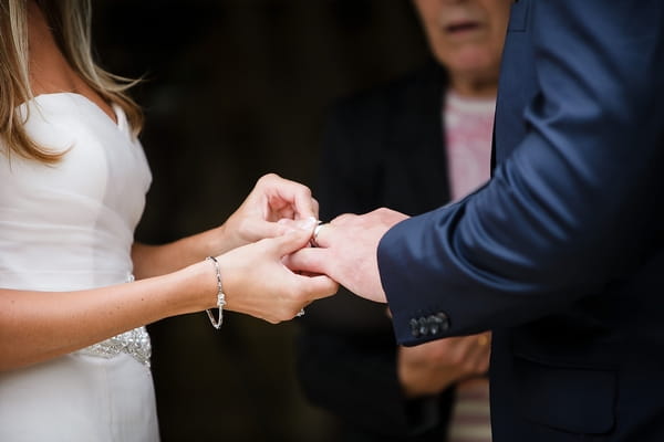 Bride placing ring on groom's finger - A Beautiful Garden Party Wedding at Lains Barn