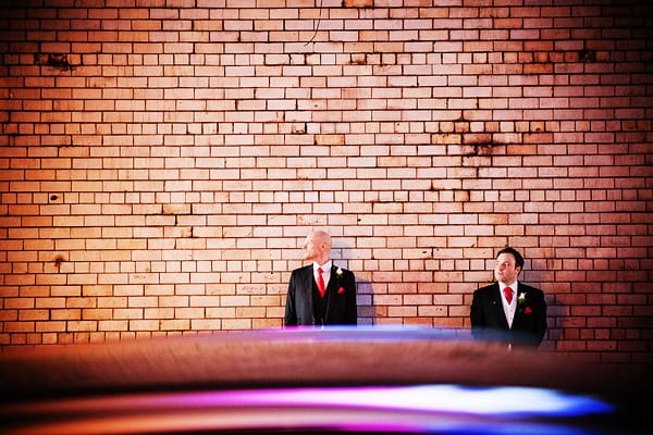 Civil partners standing by wall as car drives past - An Art Deco Themed Civil Partnership