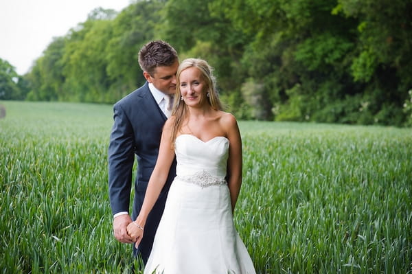 Groom holding bride's hand in field - A Beautiful Garden Party Wedding at Lains Barn