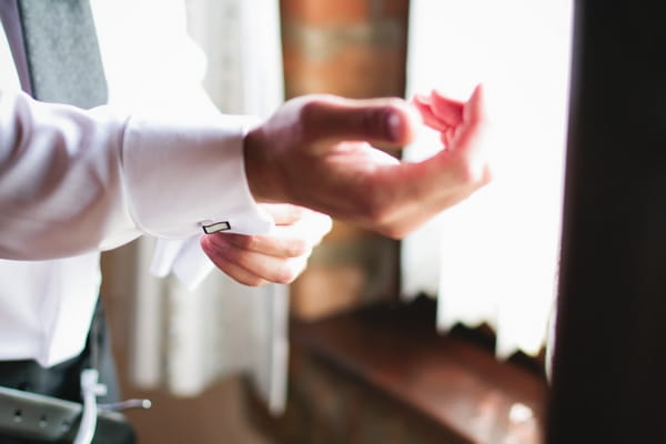 Groom fastening cufflink - A Spring Themed Wedding in Hungary