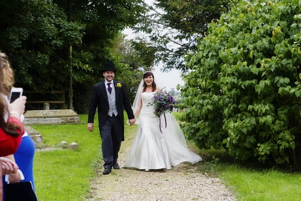 Bride and groom walking hand in hand down church path