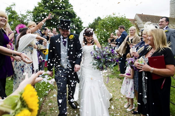 Bride and groom being showered with confetti