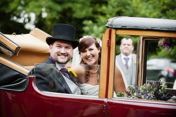 Bride and groom in back of vintage wedding car