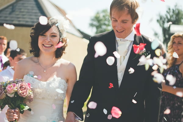 Bride and groom walking through confetti shower - A Farm Wedding with a British Summer Theme