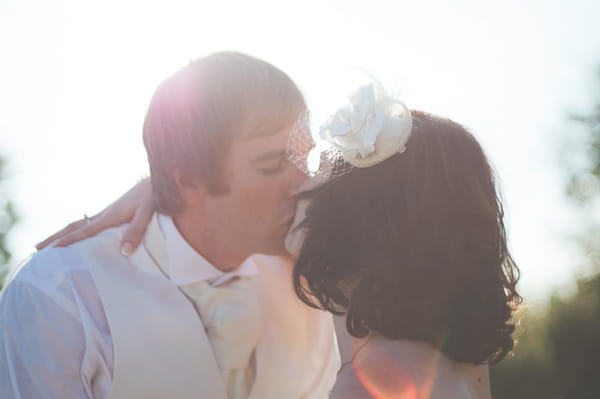 Bride and groom kiss in hazy sunshine - A Farm Wedding with a British Summer Theme