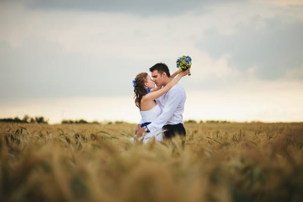 Bride with arms around groom in corn field - A Spring Themed Wedding in Hungary