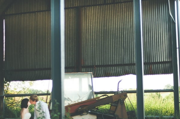 Bride and groom kissing in barn at Winkworth Farm - A Farm Wedding with a British Summer Theme