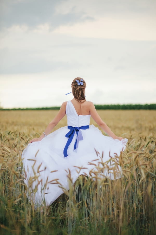 Back of bride walking through corn field - A Spring Themed Wedding in Hungary