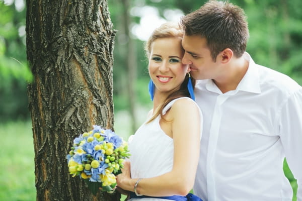 Bride and groom standing by tree - A Spring Themed Wedding in Hungary