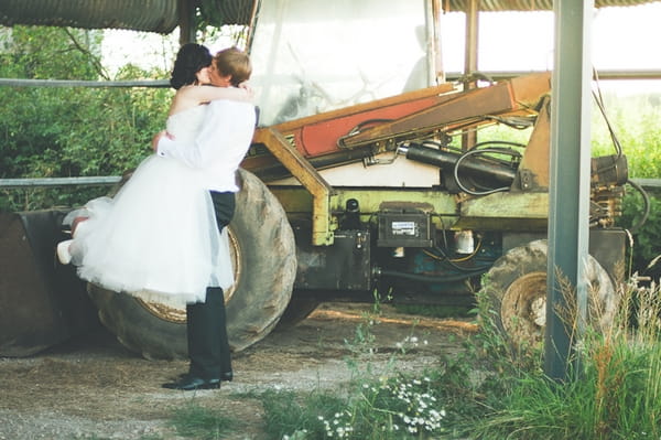 Groom lifting bride up as they kiss - A Farm Wedding with a British Summer Theme