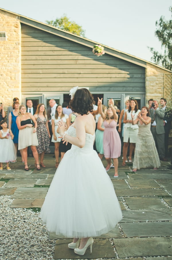 Bride looking over her shoulder after throwing bouquet - A Farm Wedding with a British Summer Theme