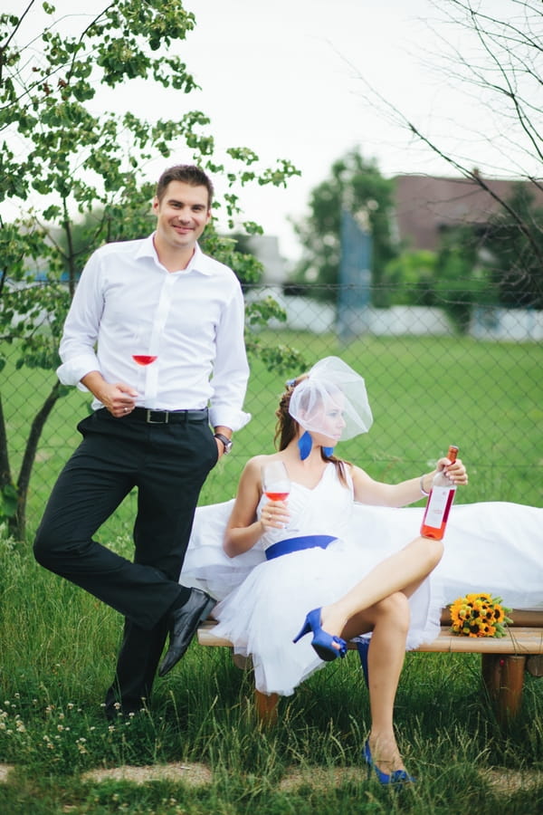 Bride and groom drinking wine on bench - A Spring Themed Wedding in Hungary