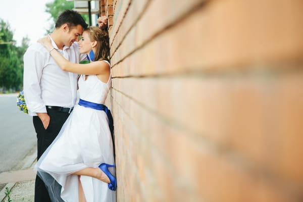 Bride and groom leaning on wall - A Spring Themed Wedding in Hungary