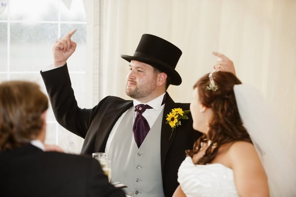 Groom pointing at his top hat