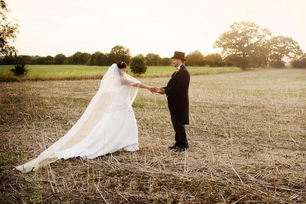 Bride and groom holding hands in field