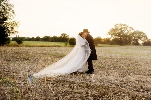 Bride and groom kissing in field