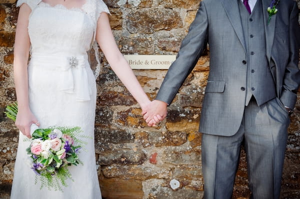 Bride and groom holding hands in front of sign - Picture by Aaron Collett Photography