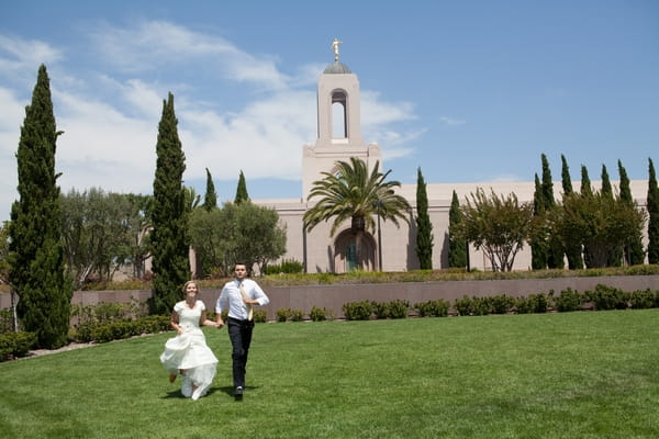 Bride and groom walking across grass at LDS Newport Beach Temple