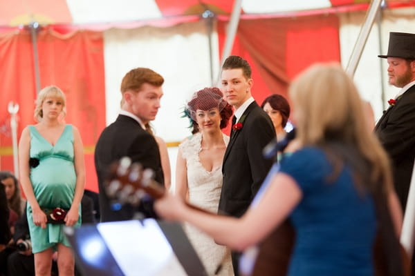 Bride and groom watching guitarist play during wedding ceremony