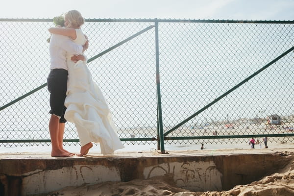 Bride and groom standing on step by beach
