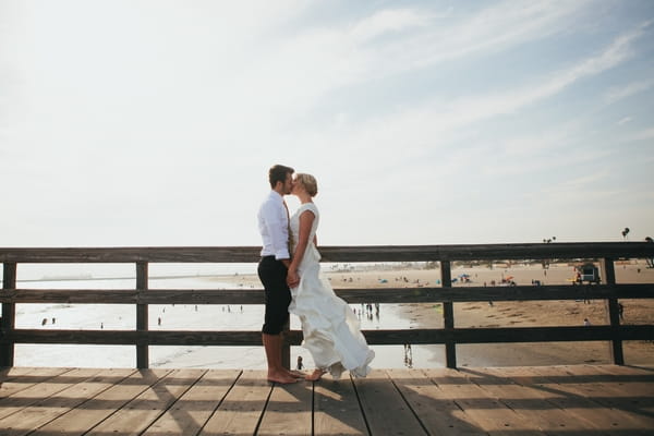 Bride and groom kissing on pier
