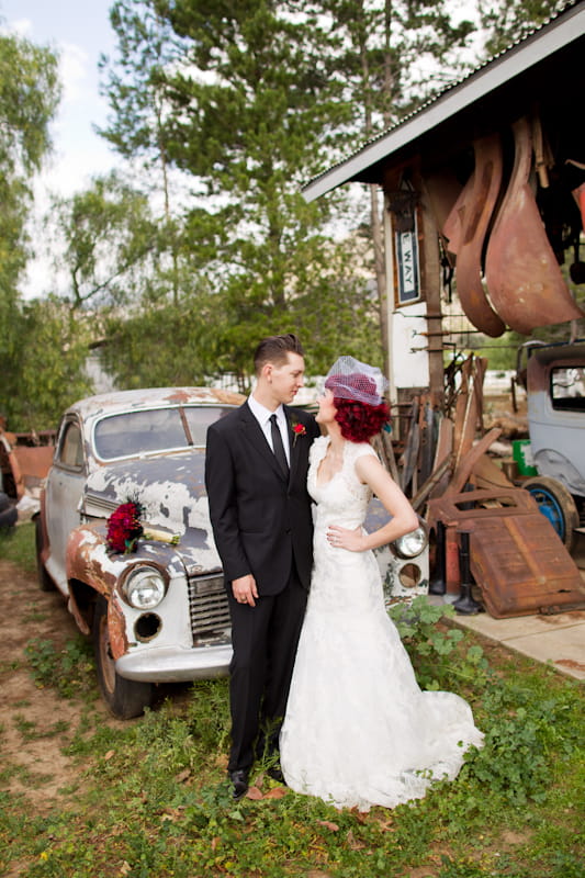 Bride and groom in front of old car