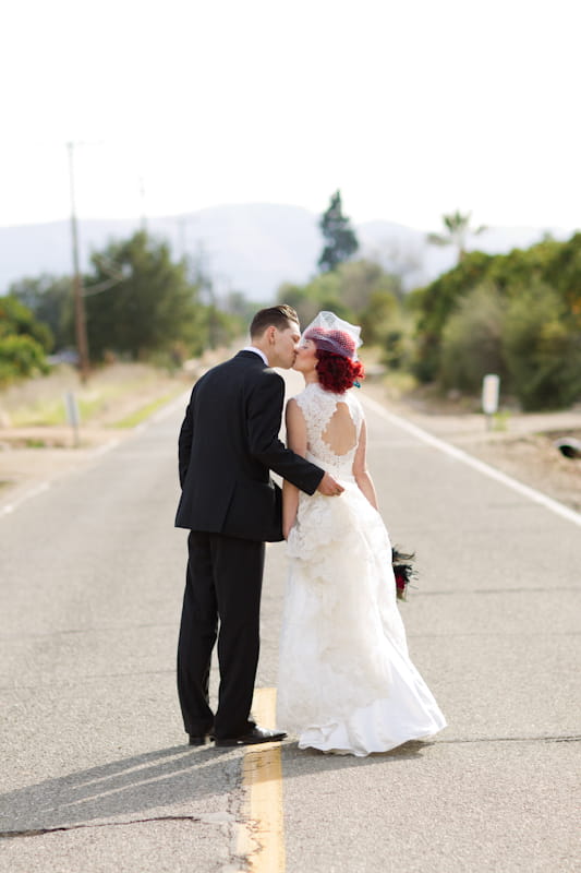 Bride and groom kissing in road