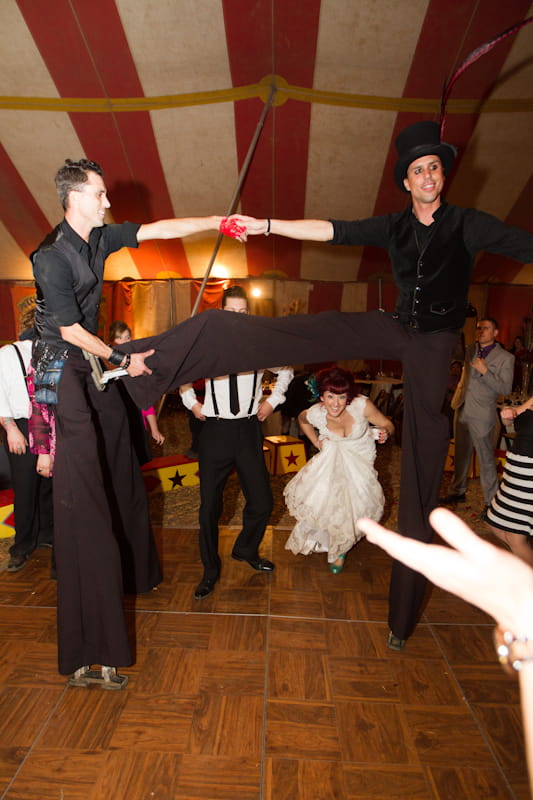 Bride and groom about to go under circus performer's leg