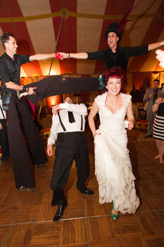 Bride and groom ducking under circus performer's leg