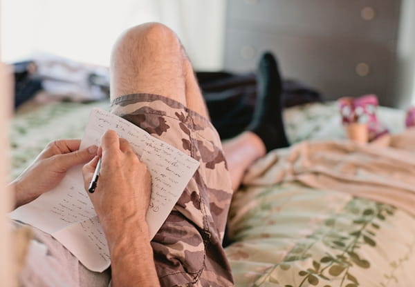 Groom laying on bed writing speech