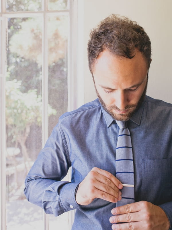 Groom putting on tie pin