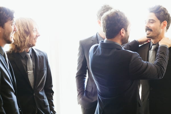 Groom adjusting best man's collar