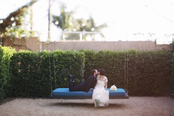 Groom laying on swing kissing bride