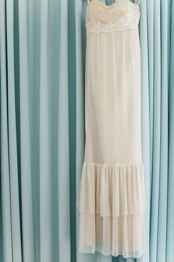 Wedding dress hanging over blue curtain