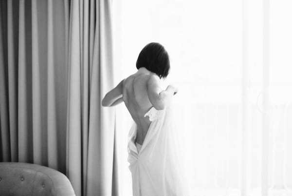 Bride putting on wedding dress