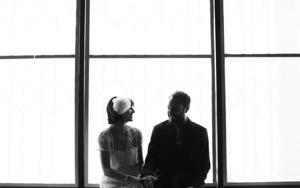 Bride and groom sitting in front of window