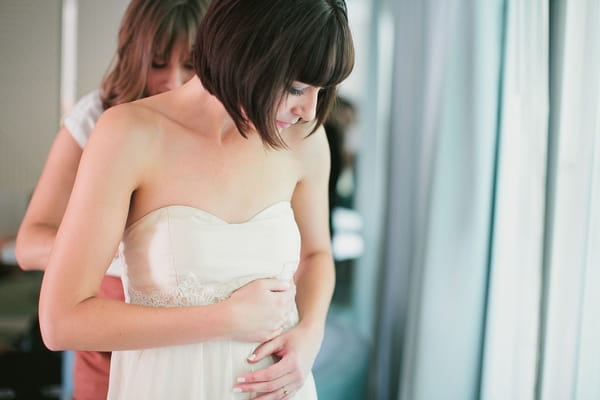 Bride having wedding dress fastened