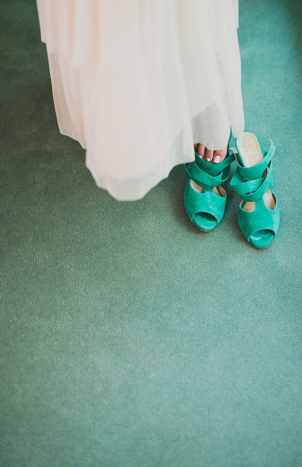 Bride putting on green wedding shoe