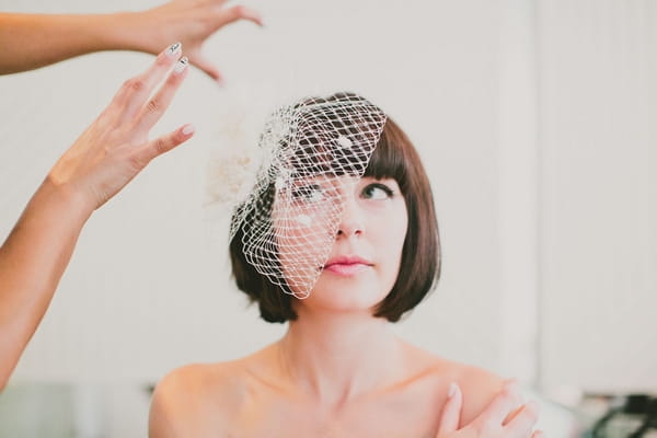 Bride putting on birdcage veil