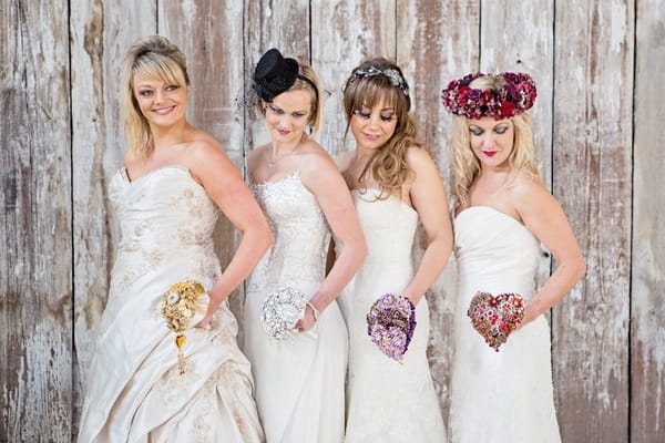 Four brides holding brooch bouquets